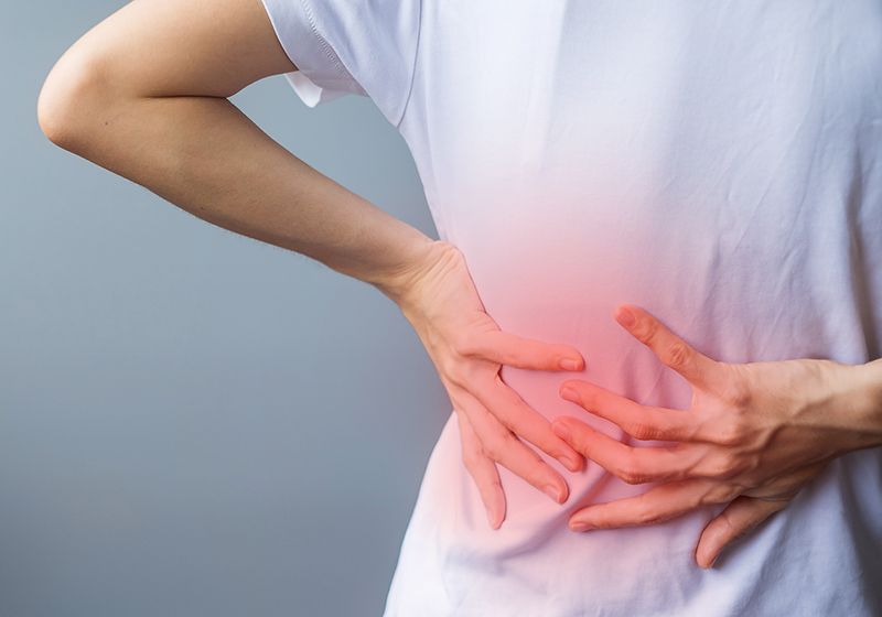 Una persona tocándose la lumbar.