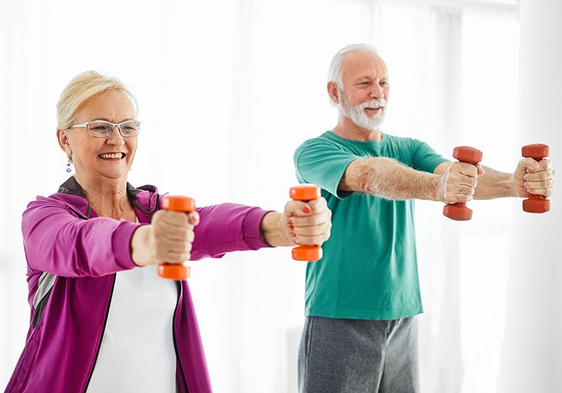 Una pareja de personas mayores realizando un entrenamiento con mancuernas.